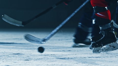 Ice Hockey Rink Arena: Professional Forward Player Masterfully Dribbles, Breaks Defense, Hitting Puck with Stick gives Perfect Pass. Star Teams Play. Cinematic Slow Motion Ground Level Shot