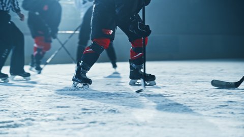 Ice Hockey Rink Arena: Professional Forward Player Masterfully Dribbles, Breaks Defense, Hitting Puck with Stick gives Perfect Pass. Star Teams Play. Cinematic Slow Motion Knee Level Shot
