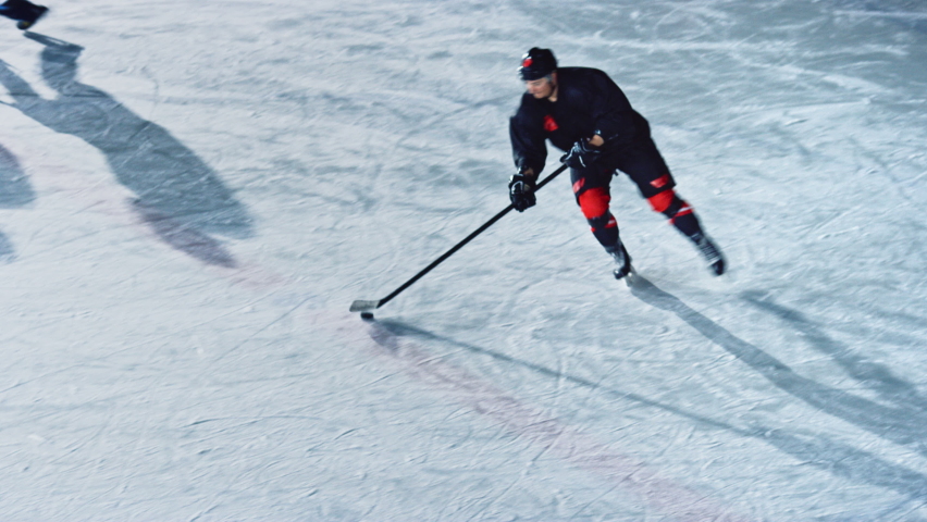 Ice Hockey Rink Arena: Professional Forward Player Masterfully Dribbles, Breaks Defense, Hitting Puck with Stick Scores Goal, Goalie Missed it. Fast, Energetic, Cinematic High Angle Tracking Shot | Shutterstock HD Video #1073573978