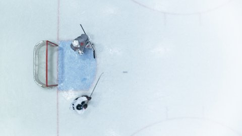 Top View Ice Hockey Rink Arena: Professional Forward Player Masterfully Dribbles, Breaks Defense, Hitting Puck with Stick Scores Goal, Goalie Missed it. Flying Aerial Drone Shot