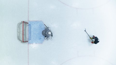 Top View Ice Hockey Rink Arena: Professional Forward Player Masterfully Dribbles, Breaks Defense, Hitting Puck with Stick Scores Goal, Goalie Missed it. Aerial Drone Static Shot
