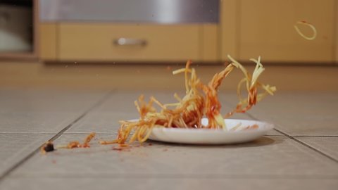 Plate of spaghetti dropped on the kitchen floor in slow motion from 120fps. Plate and food surviving the fall