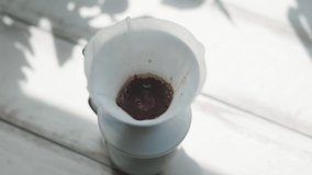 Process of making pour over coffee. Filter with ground coffee is filled with boiling water from a kettle with a goose nose. Top view, close-up. Real time. Soft focus.