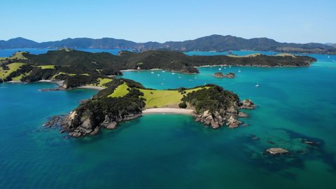 Picturesque sandy beach surrounded by cliffs and lush green hills aerial. Urupukapuka Island, New Zealand