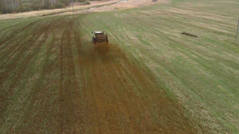 Natural eco fertilizer. Farmer increases the yield of arable land by spreading manure. Aerial rear view of a farm vehicle with a trailer unit