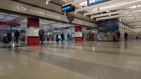 Chicago IL USA - May 11 2021: Turnstile entrance to O'hare Blue Line Station in the middle of a weekday. Passengers and crew exit the station to connect to flights. Face masks for COVID-19