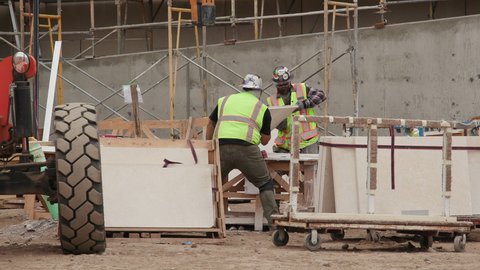 San Diego, California, USA - June 7, 2019: Stonemasons are receiving and organizing a shipment of stone that will be installed on the exterior walls of a new building that is under construction.