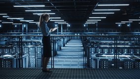 Female IT Specialist Using Tablet Computer in Data Center, Walking on a Bridge Overlooking Big Server Farm Cloud Computing Facility. Businesswoman, e-Business Entrepreneur. Pedestal Wide Shot - Powered by Shutterstock - Get 15% off with code: PIKWIZARD15