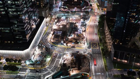 Hyperlapse time-lapse of car traffic transportation, crane under construction site at night in Singapore city downtown. Drone aerial view. Industrial business or civil engineering technology concept