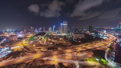 Aerial time lapse of Johor Bahru city with tall buildings in clear sky at night and busy traffic on elevated highway leading to CIQ. Prores 4KUHD