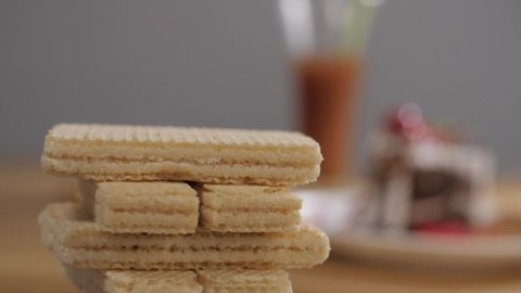 A pile of white cream filled crunchy wafer biscuit snack crackers rotating slowly. Close up shot of delicious fresh waffle dessert stacked neatly on top of each other - crispy sugary food
