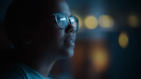 Portrait of a Teenage Multiethnic Black Girl Looking Out of the Window in Excitement. Surprised Young Female Watching the Night Sky from Her Home. She Wears Glasses and Dental Braces.
