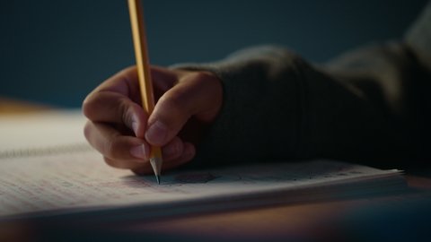 Authentic Close Up Footage of a Young Person Writing with Pencil in Notebook. Teenager Making Homework for School. Education Concept.