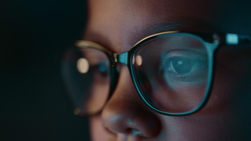 Close Up Portrait of a Cute Young Teenage Multiethnic Black Girl in a Dark Cozy Room at Home. Young Female Wears Glasses that Reflect School Homework from Her Laptop Computer Screen in Them. Royalty-Free Stock Footage #1073619539