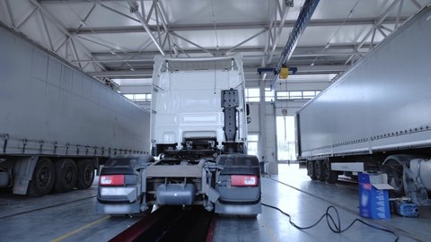Panorama at the service station of trucks with semi-trailers and refrigerators. Lorry are in the truck service on the inspection pit.