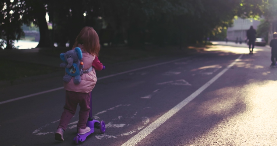 happy baby girl scooting on scooter on the crowded street, active lifestyle