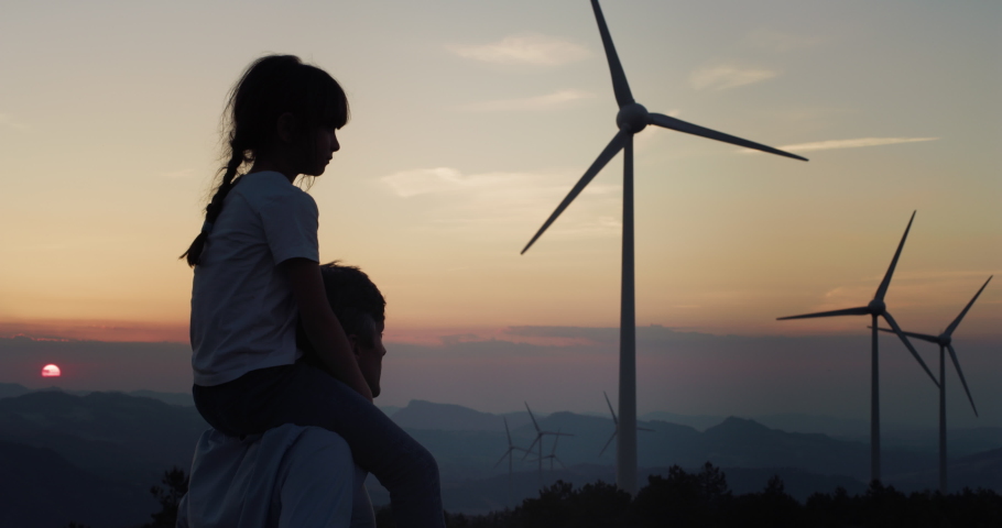 Father and Daughter in a Wind Farm Watching and Pointing at Wind Turbines at Sunset. Aesthetic Shot for Concept of Green Energy and Eco Friendly Environment for Future Generation and our Children Royalty-Free Stock Footage #1073628749