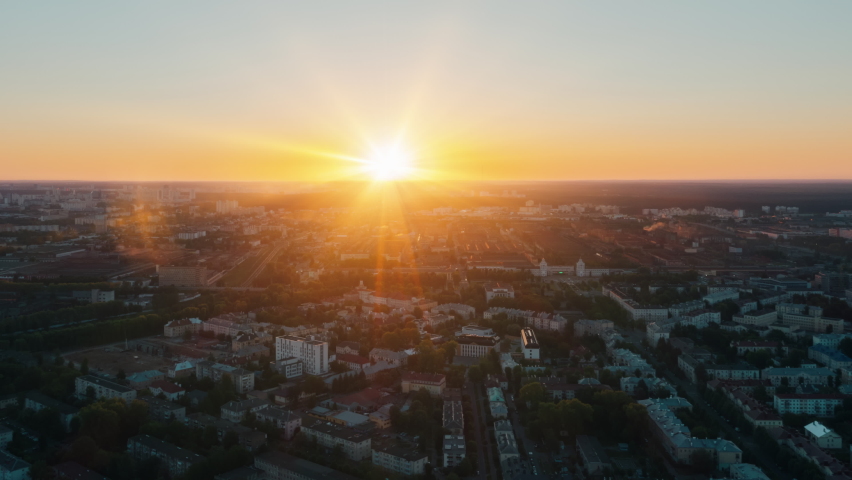 Aerial time lapse hyperlapse sunrise over big city, morning cityscape. Drone flight over industrial landscape. Bright sun beams on horizon. Belarus, Minsk at dawn overlooking city skyline