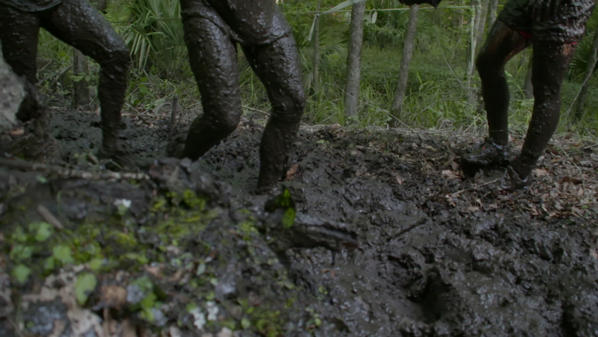 people running a mud race high speed and slow motion
