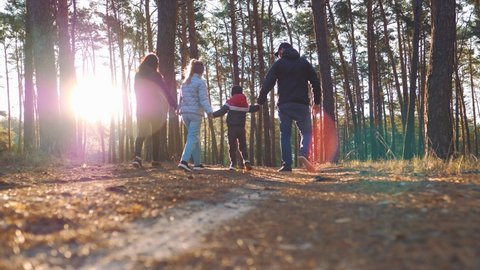 Happy family hiking through a forest. Parents with kids walking by hiking trail. People having fun on a trekking day. Group team on hike in forest. Travel vacations and family concept.