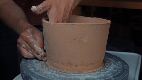 Potter making ceramic pot on the twisted pottery wheel. Top view. Potter at work, close up. Handmade, craft. White clay