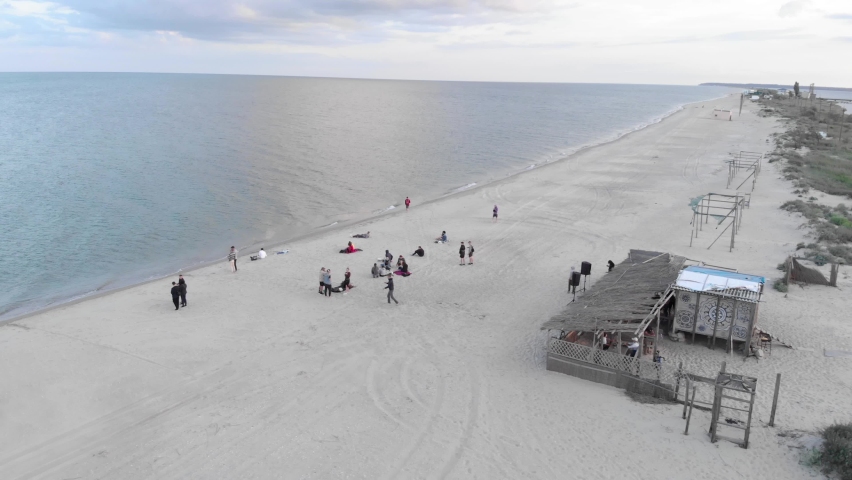 Summer beach party at sunset. Friends having party at beach, drinking beer, laughing and relaxing. Party on beach. Vacation, holiday