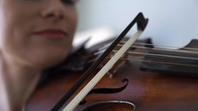 Close-up of The hand of a girl playing the violin. The bow is moving along the strings extracting music.