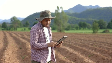 Smart farmer checks quality of soil before sowing with a tablet. The farmer tests soil the growth quality of seedling.Agriculture concept.