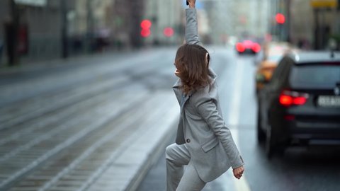 a middle-aged woman with an orthopedic collar around her neck dances and rejoices against the background of a blurred city street and passing cars. she holds the phone in her hand
