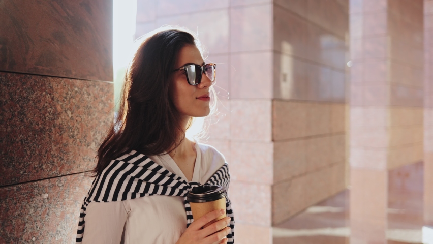 Look what I bought. Waist up portrait view of brunette girl in casual clothes holding colorful shopping bags and smiling to the camera while drinking coffee at the street
