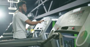 Cropped view of the young woman in sportswear started running on treadmill at the gym with a lot of people at the background. Stock video