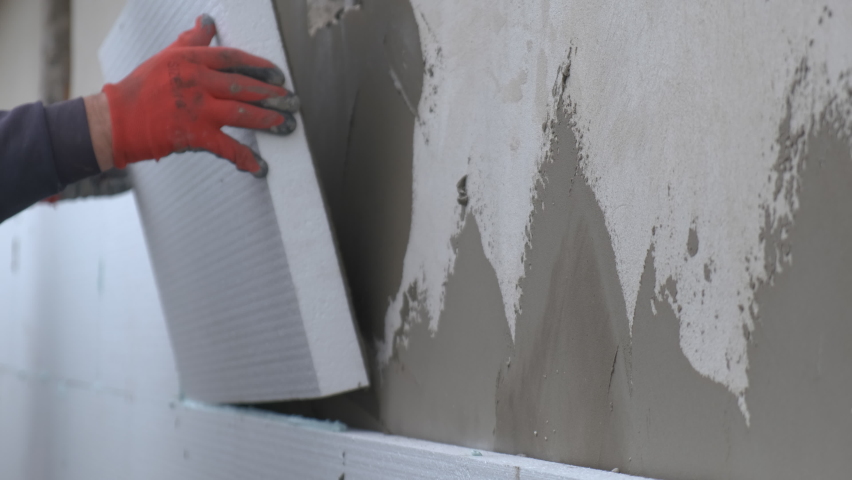 Construction worker installing styrofoam insulation sheets on house facade wall for thermal protection. | Shutterstock HD Video #1073679428