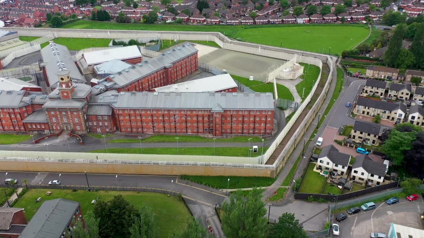 Aerial drone footage of the town centre of Wakefield in West Yorkshire in the UK showing the main building and walls of Her Majesty's Prison, also know as HMP Wakefield taken in the summer time Royalty-Free Stock Footage #1073680361