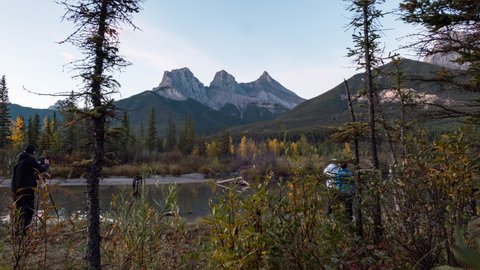 Time-lapse Zoom in of Group of photographer taking a photo at Three Sisters Mountains are rocky mountains in autumn forest at Canmore, Banff national park, Canada