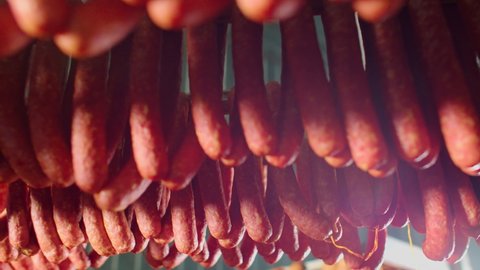 Meat delicacies on the metal frame. The production technology of sausage and smoked meat. Appetizing smoked. Tasty food and groceries. Cooking delicious . Salami. Meal Factory. Rows of ham.