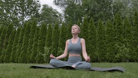 young woman practicing yoga on the grass in the garden