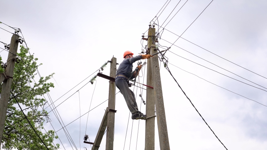 The electrician connects the lighting cable. In the village. The worker has finished work. The electrician descends from the post. Protection against electrical shock. Royalty-Free Stock Footage #1073730749