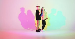 Cool dancing young couple in colourful neon studio light. Contemporary expressive dance with passion, hip hop dancers