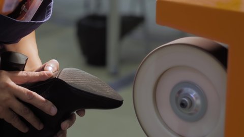 Shoemaker, shoes master using automatic shoe polish machine tool for polishing black leather women footwear at workshop - close up