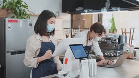 Asian cafe owner couple wear face mask due to Covid19 pandemic, check in sale order from laptop computer on counter bar in restaurant feel happy for income. Entrepreneur and Economic of small business - Powered by Shutterstock - Get 15% off with code: PIKWIZARD15