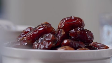 Hand Picks Up Sweet Date Fruit From Heap In A White Bowl. - Close Up Shot