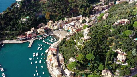 Aerial view with a drone above the coast of Portofino in Italy. We can see boats, blue water near the houses in the mountain 4K
