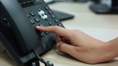 slow motion scene of  employee woman hand point to press button number on telephone office desk for hotline employee concept