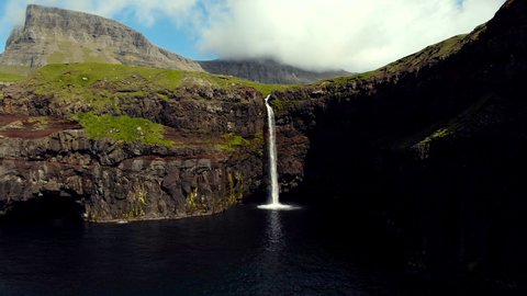 Mulafossur Waterfall near Gasadalur village on the coastal of Vagar Island, The Faroe Islands. Backward aerial flight