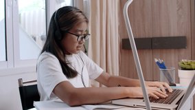 4K Learn from home concept. Asian girl students learning virtual internet online class by remote meeting due to covid-19 pandemic. Girl student learning online with laptop at home