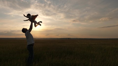 Father and little child play, laugh and hug together. Dad throws up a happy daughter in the blue sky. Enjoyable family travel. Baby in the arms of the parent. Dad day off. The concept of happy family