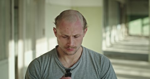 Stressed man shaving head in hallway