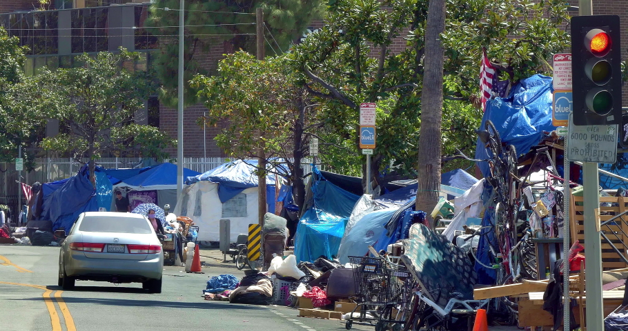 LOS ANGELES, CALIFORNIA, USA - APRIL 8, 2021: Mercedes car passes homeless and mental ill people living in tent camp during homelessness crisis and coronavirus COVID-19 pandemic in Los Angeles, 4K
