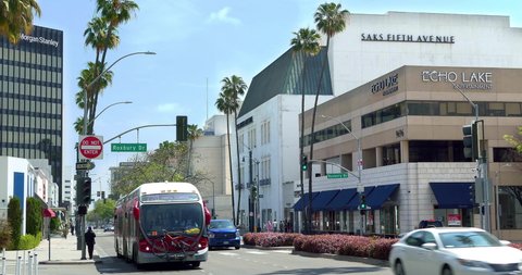 LOS ANGELES, CALIFORNIA, USA - APRIL 6, 2021: Cars traffic on Wilshire Boulevard near Saks Fifth Avenue luxury department store and Echo Lake Entertainment Company in Beverly Hills, Los Angeles, 4K
