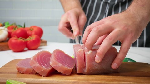 Chef slicing raw tuna yellowfin on a table into a big steak size in 4K. Healthy meat, fresh tuna being cut in pieces on a chopping board for a tuna steak.